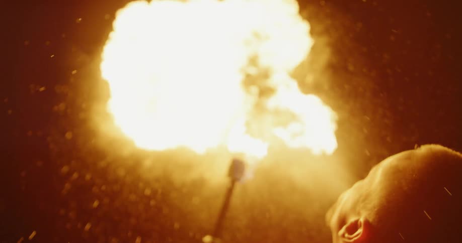 A man holding a torch blows and breathes fire
