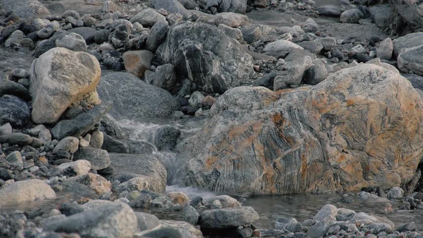 A stream flows down over rocks and boulders