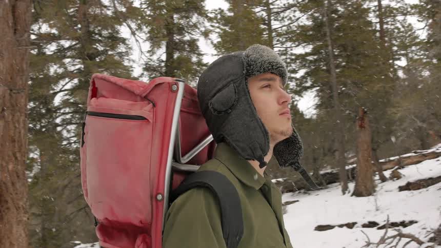 Man walking over to some woods as it snows