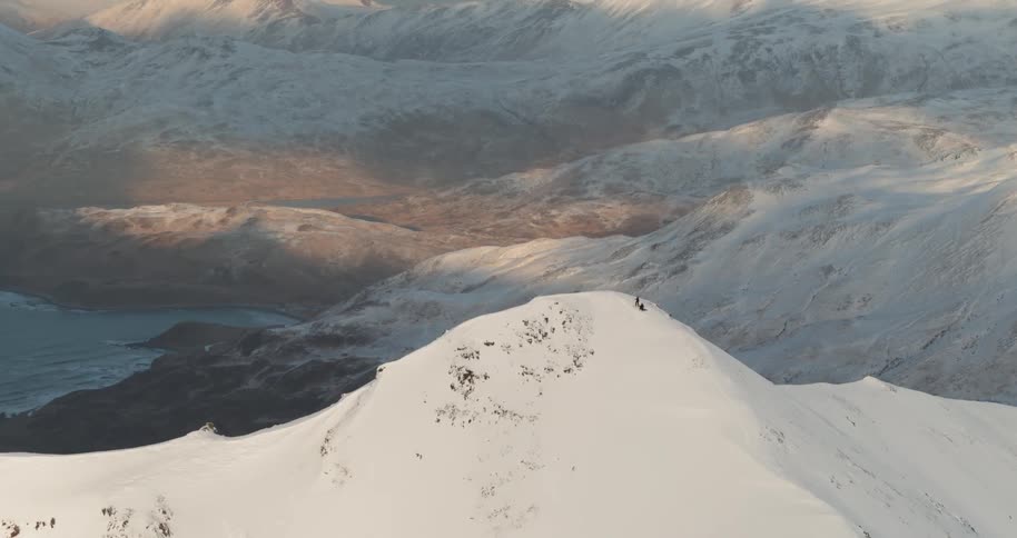People are at the top of a snow covered slope overlooking the ocean