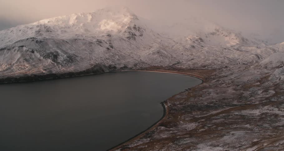 Snowy mountains surround a bay at sunrise
