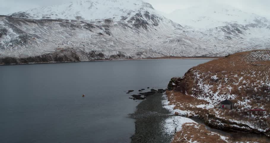 A person kayaks on a snowy mountain shore
