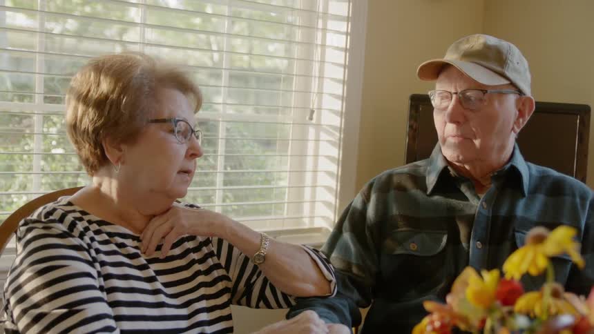 A man and woman talk at a dining room table