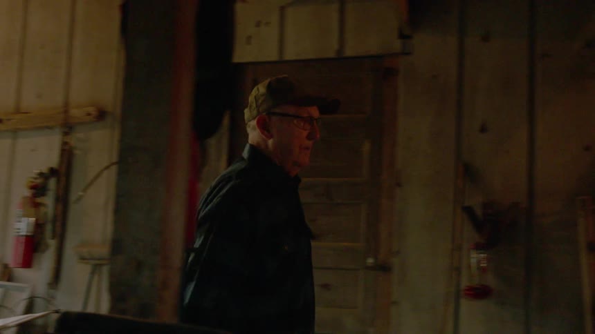 An old man is walking into his tool shed