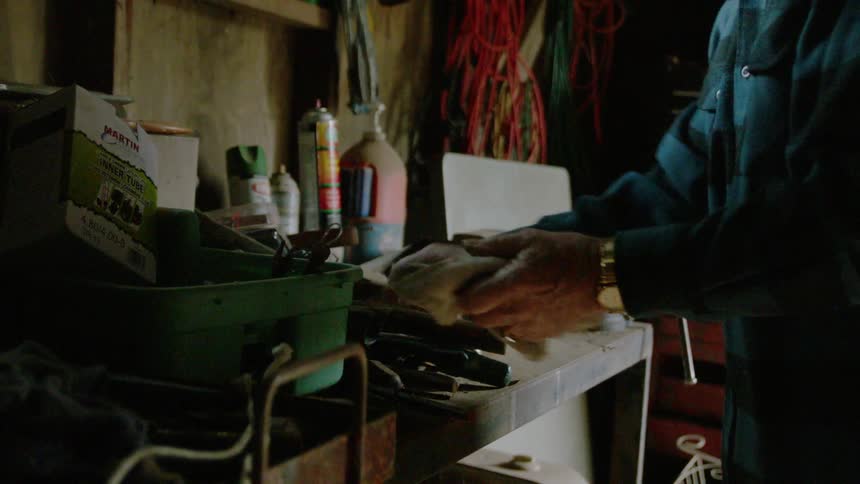 An elderly man cleans a shop bench