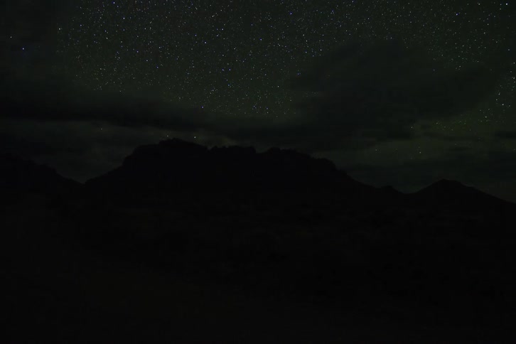Storm clouds pass over mountains in a desert as time lapses