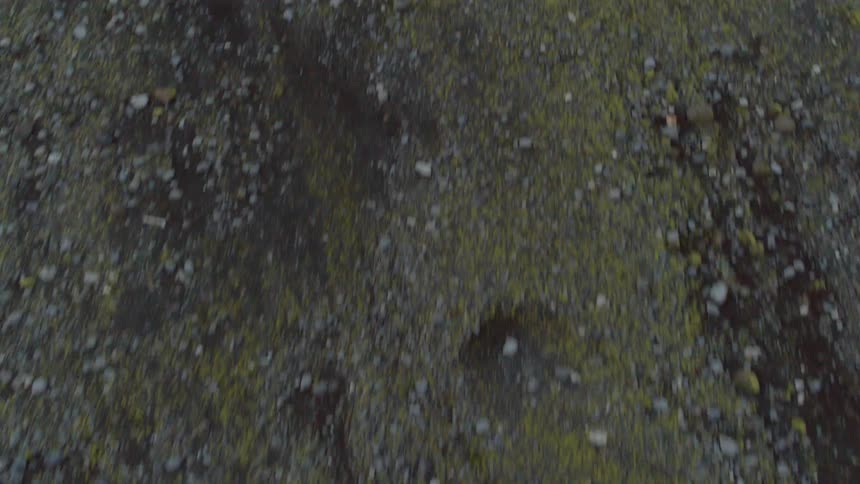 A drone is flying over a dirt and rock covered hill
