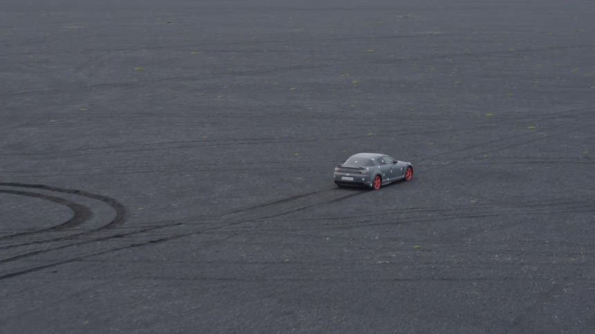 Car driving and leaving tracks on a flat dirt area
