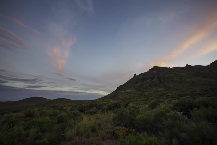 Time lapse of clouds flying past a cliff side in the desert