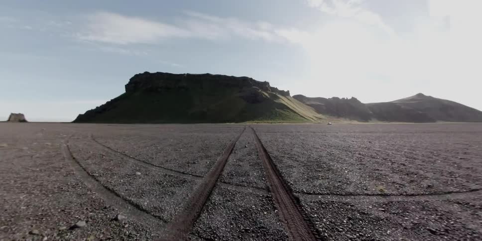 Narrow car tracks across a dirt plain