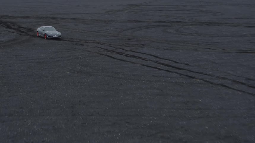 A sports car is off-roading in the sand at dusk