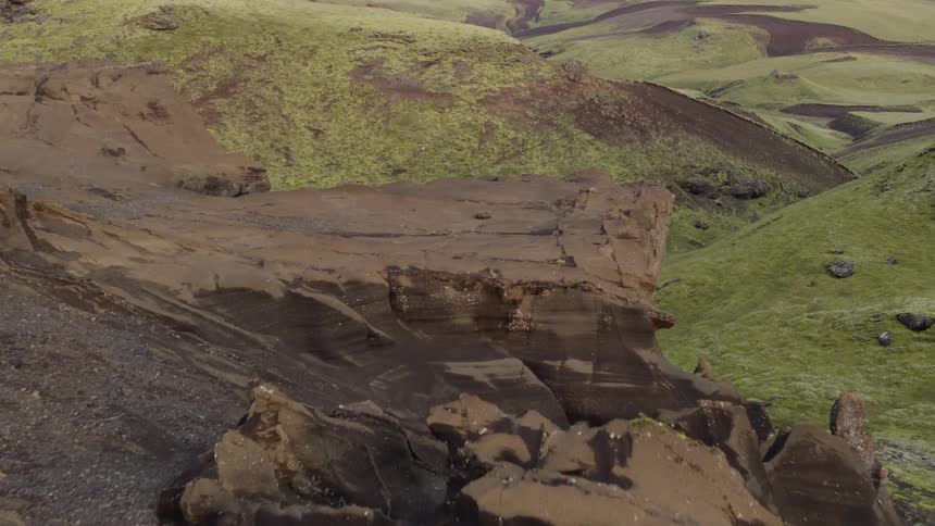 Jagged rocks and ledge overlook green valley and hills