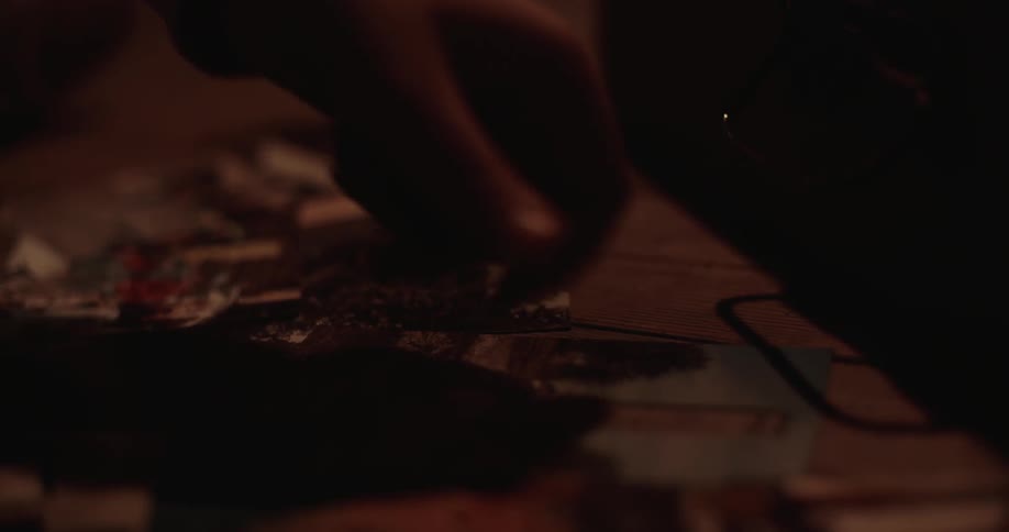 Person moving something in the dark and holding a lighted match