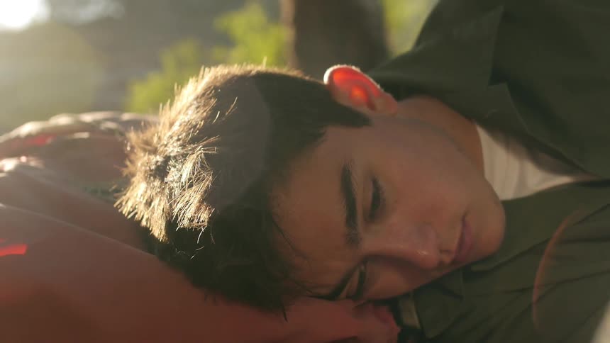 A close view of a young man waking up in the morning from sleeping outdoors on the ground