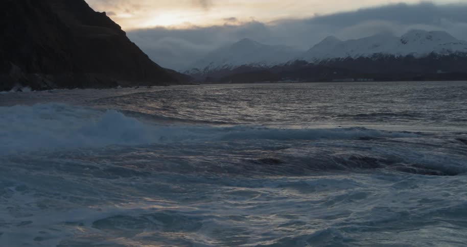 Waves splash and break over rocks at sunset