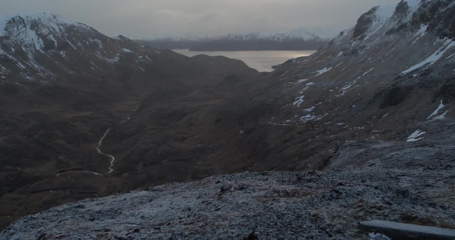 Snowy mountains surround a lake at sunset