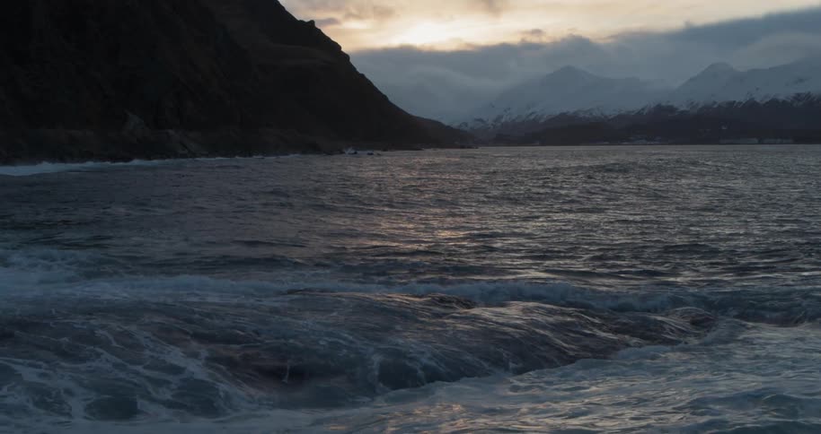 Waves are crashing ashore at sunset