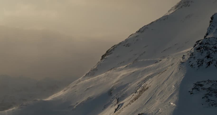 Snow blows around a mountain ridge