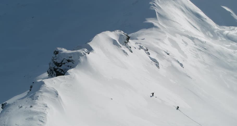 Two skiers are climbing up a snow-covered mountainside during the day