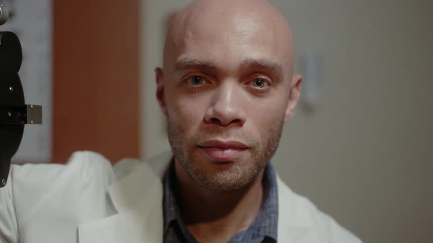 Eye doctor removes eye machine and gazes at patient