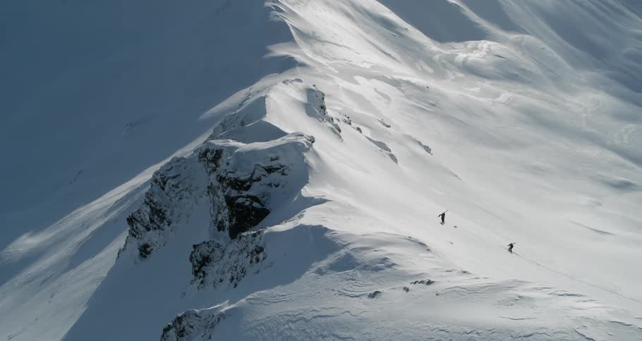 Two skiers are climbing up a snow covered mountain side