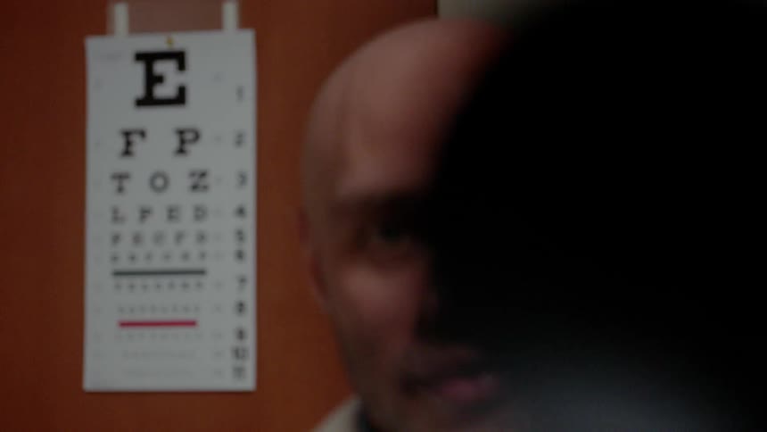 Man's face and an eye chart behind