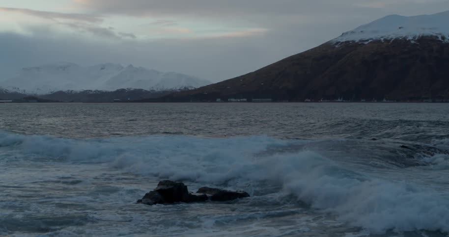 Waves crash over rocks near an island
