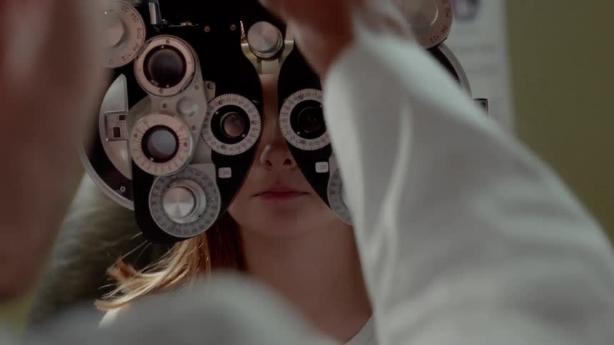 An eye doctor is giving someone an eye exam