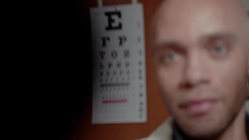 A man is in the optometrist office and looking at an eye chart