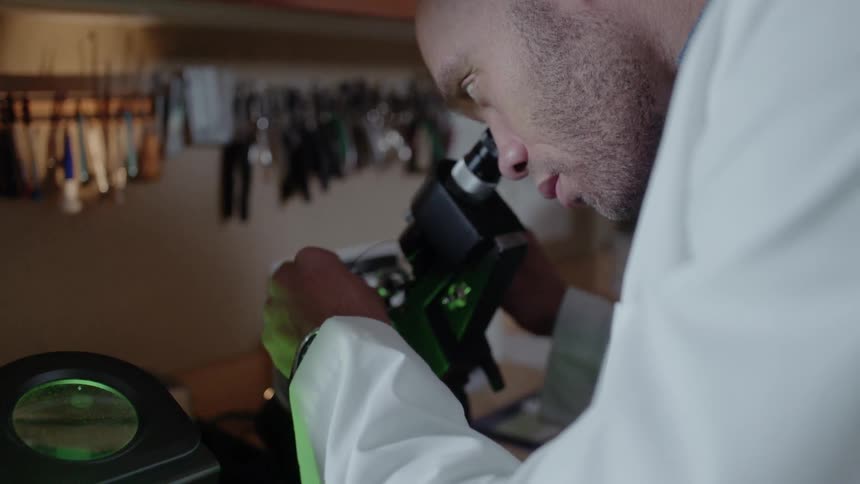 Doctor examines something under a microscope