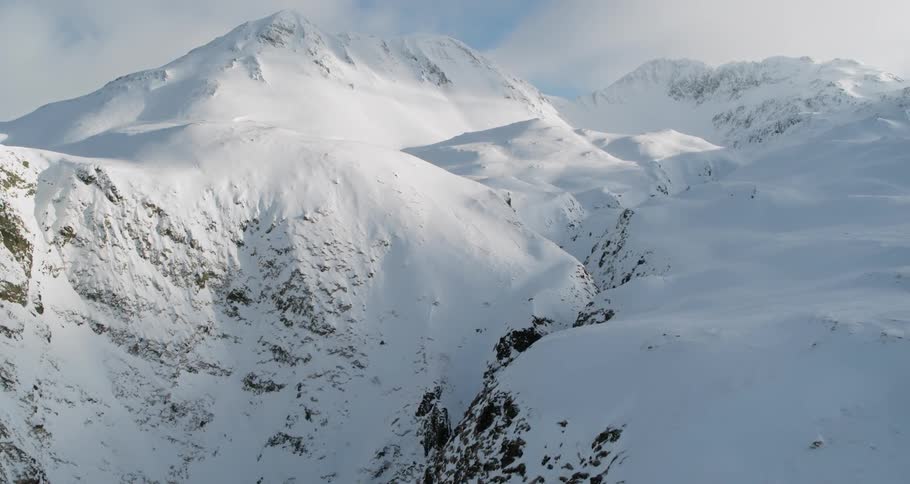 Clouds float above snowy mountains and a gorge