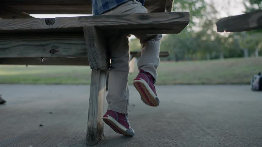 A child dangles his legs from a bench