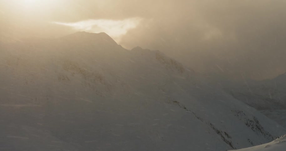 Snow falls on a mountain slope on a cloudy day
