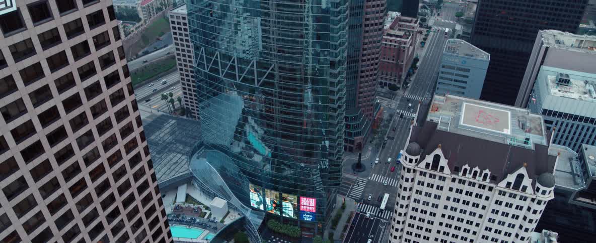 Traffic moving through a large city street surrounded by skyscrapers