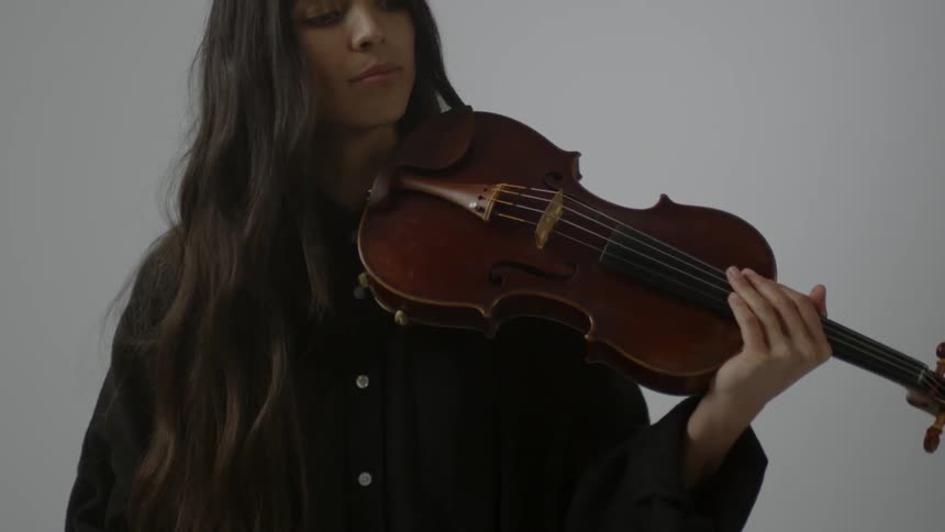 Woman picks up a violin and puts it under her chin to play