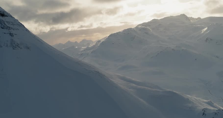 Snow covers mountains on a cloudy day