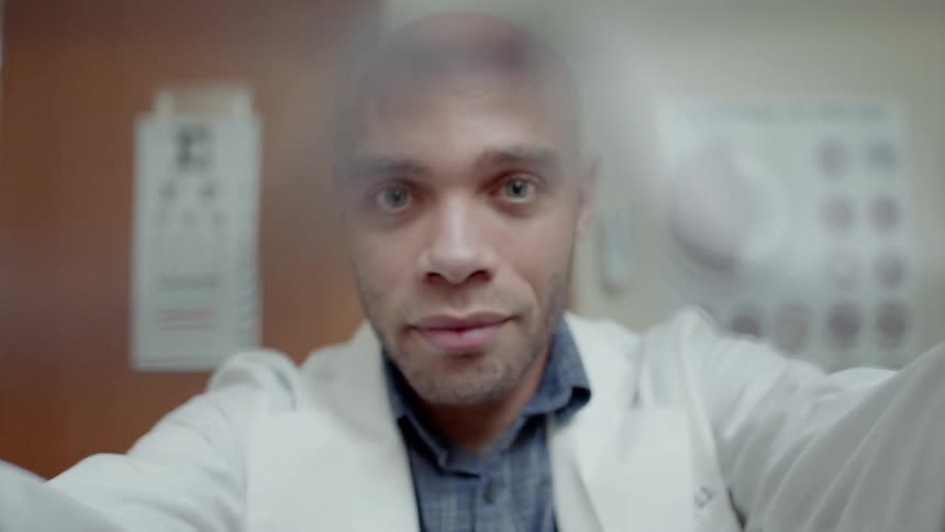 An optometrist places glasses on a person