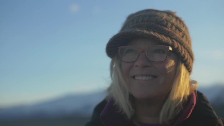 A woman smiles as she stands in a canyon and looks around