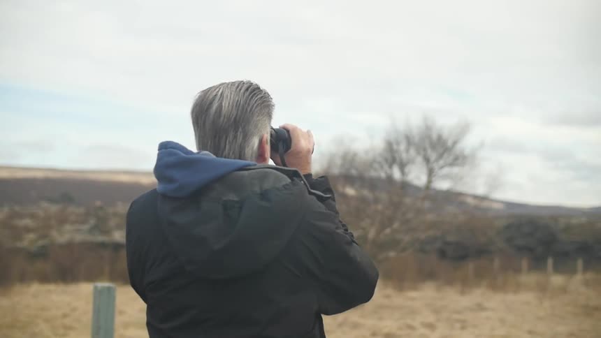 Man taking photos of a field on a cloudy day