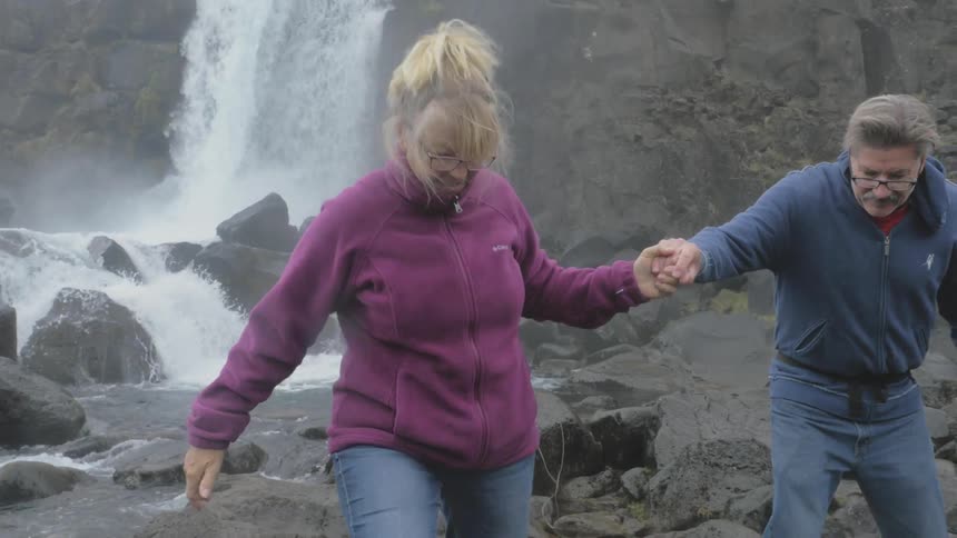 A couple is walking next to a stream