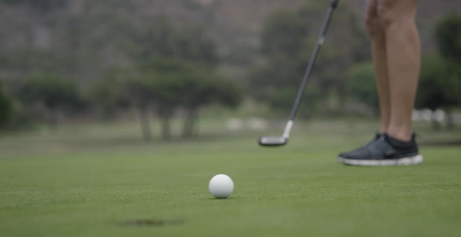 Someone is putting a golf ball into the hole but misses