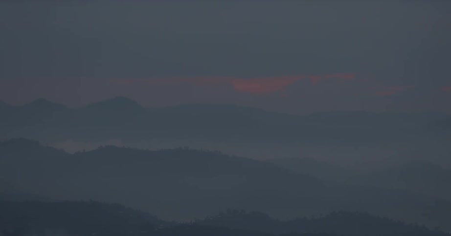 Misty valleys and hills are viewed from atop a mountain