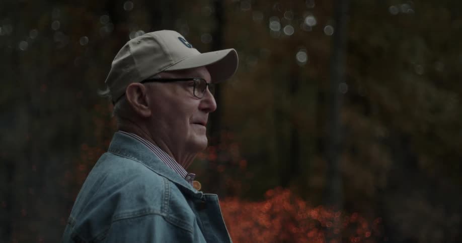 A man stands next to a campfire in the woods