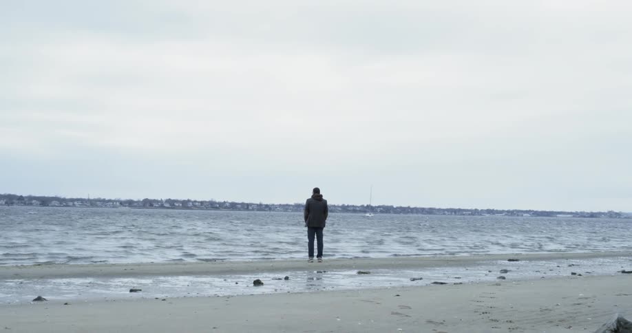 A man stands on a lakeshore