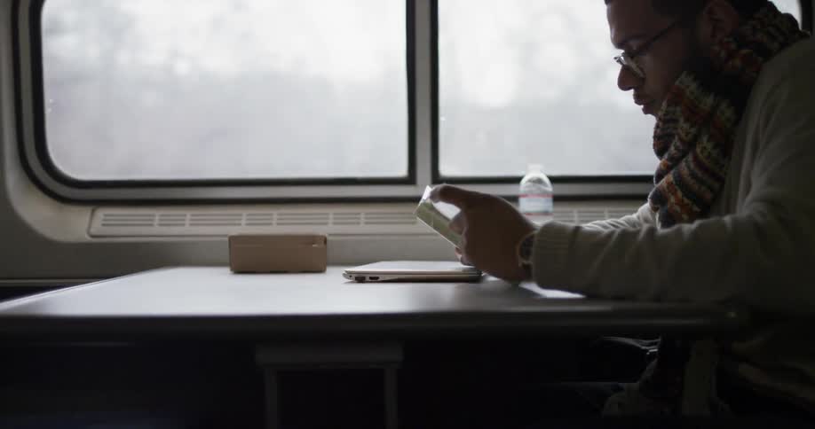 A man sits on a commuter train and reads a book