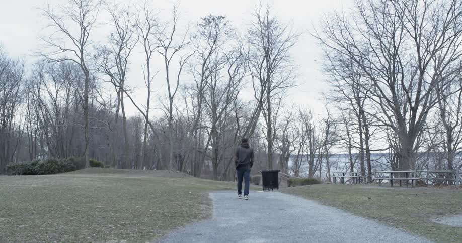 A man walks in a park on a windy day