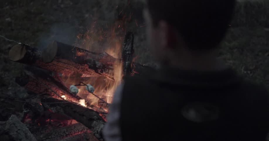 A kid is roasting marshmallows on a stick outside