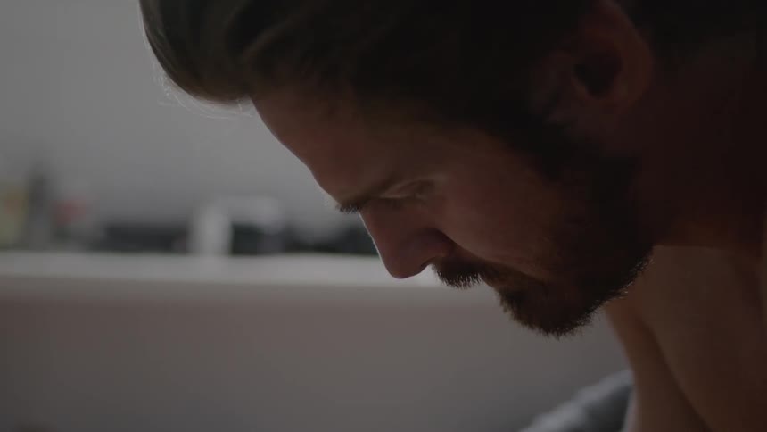 A man is sitting in thought in a room during the day