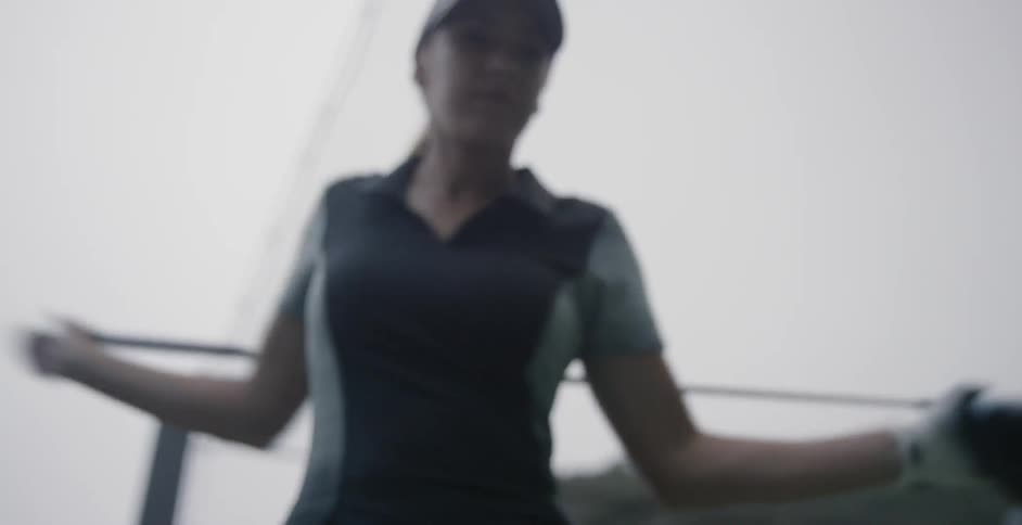 A female golfer is holding a driver behind her back as she stretches and twists