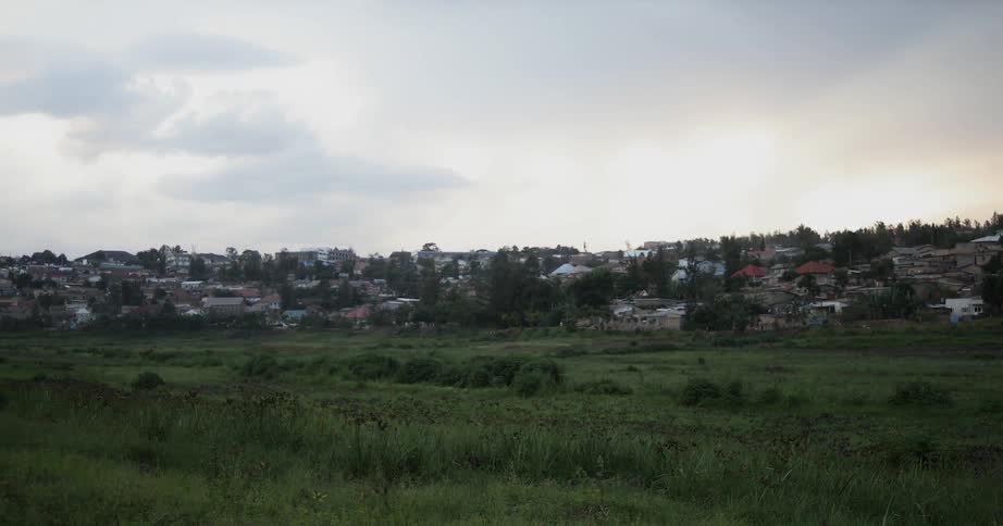 Clouds float above houses and a grassy field